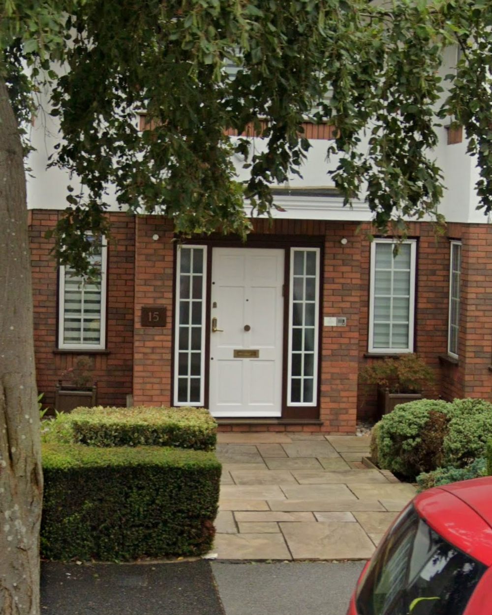 Close-up of the white panelled front door with glazed side lights and the number 15 plaque